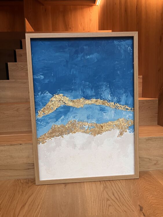 Taevateemaline abstraktne maal elevandiluvalge ja sinisega, mille keskel on kaks allapoole suunatud struktuurset kuldset kaart.