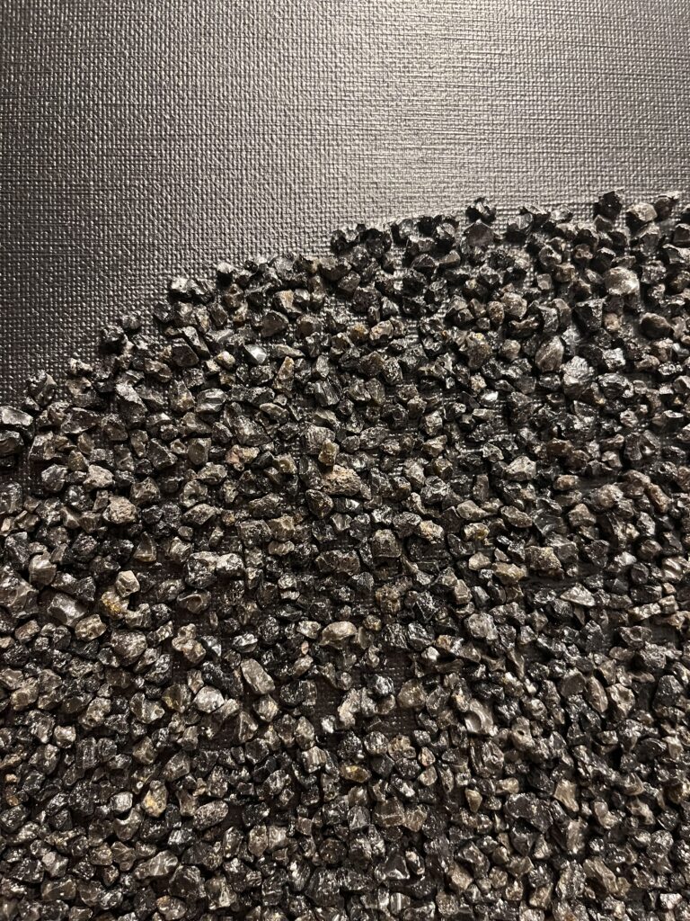 Mustal taustal struktuurmaal Kuukivi, kus sätendavad kivikesed on paigutatud keskele suurde ringi, sümboliseerides kosmilist energiat.