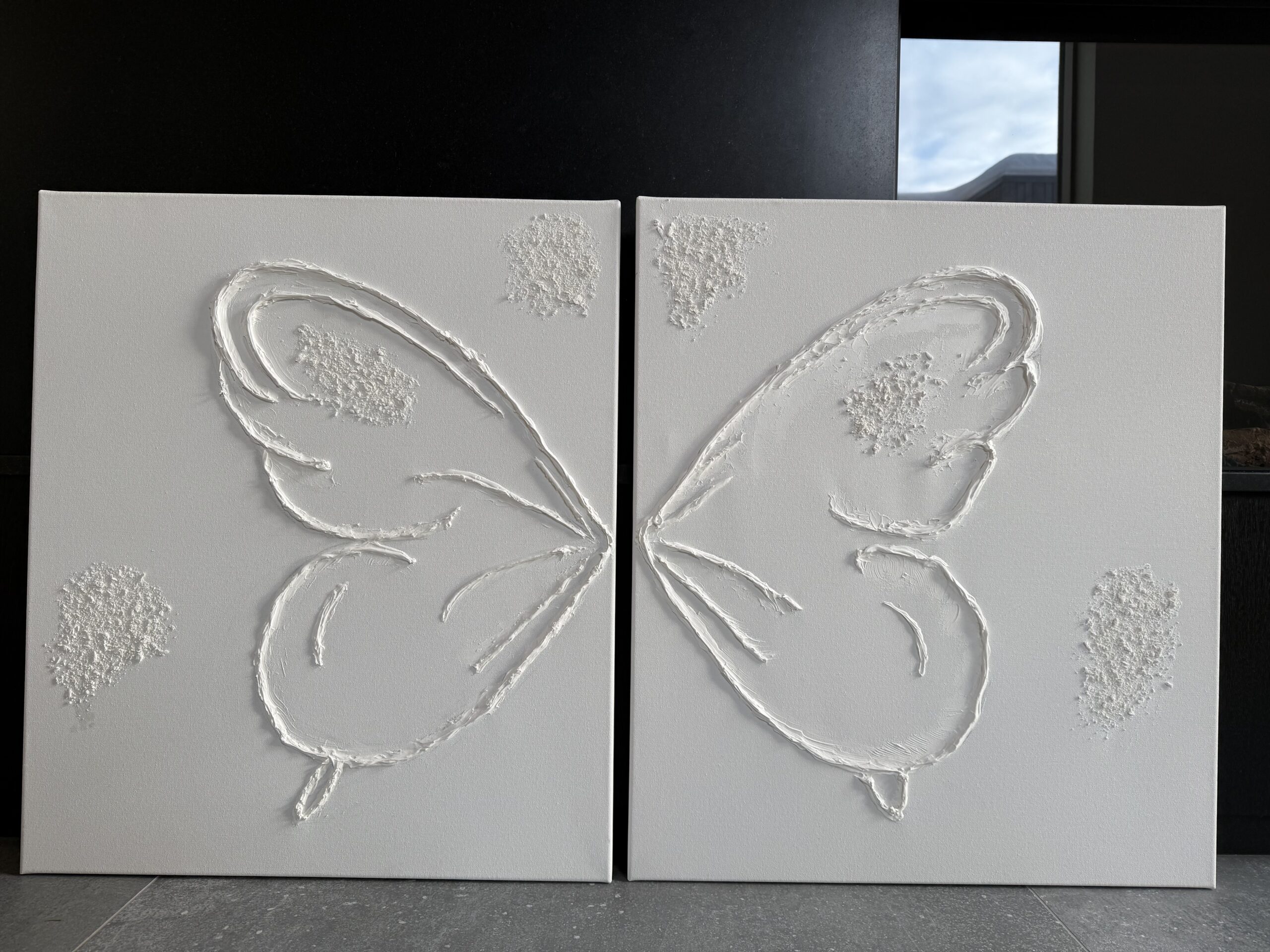 Kaheosaline lumivalge struktuurmaal liblikas. Minimalistlik akrüülmaal kahel lõuendil, kus tekstuuriga on moodustatud poolitatud liblika tiivad.